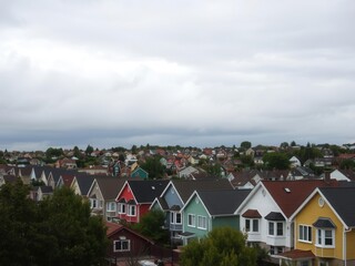 Colorful houses with muted tones set against a cloudy sky in a suburban neighborhood, residential, weather