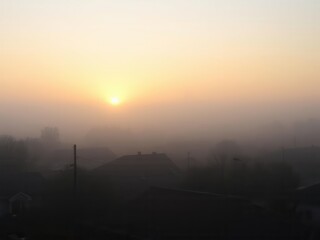 Foggy dawn with soft sunlight breaking through in tranquil neighborhood, houses, peaceful