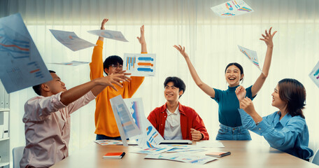 Excited and happy startup company employee celebrate and throw paper in the air after make...
