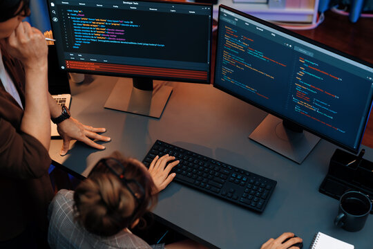 Top view of IT developers discussing with point to intelligent website development coder system running data online two screens information technology at neon light room at modern office. Infobahn.