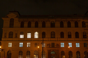 Fototapeta premium Historic architecture with beautifully lit windows during the night hours, showcasing intricate urban design elements and a captivating nighttime ambiance for all to admire