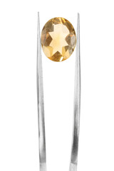 Tweezers with shiny yellow gemstone isolated on white