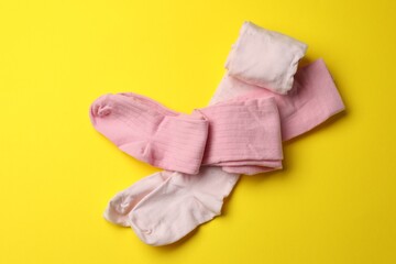 Pink child's tights on yellow background, top view