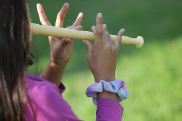 Young girl playing recorder flute outdoors in nature: