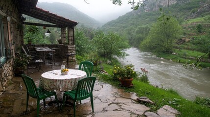 Obraz premium Rainy Day Cafe Patio River View Stone House Green Chairs