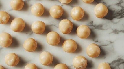 Close-up view of salted macadamia nuts arranged on a marble surface, beautifully illuminated by natural light, showcasing their smooth texture and glossy appearance.