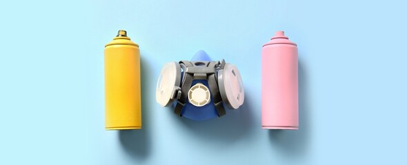 Spray cans and respirator on light blue background, top view