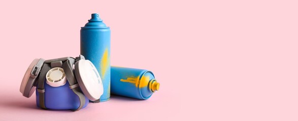 Respirator and spray cans on pink background with space for text
