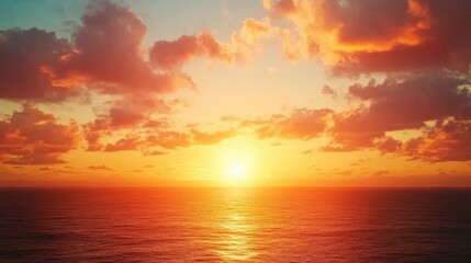 Obraz premium Vibrant sunset casting warm orange and yellow hues across a peaceful sea, with fluffy clouds reflecting the colorful sky, creating an idyllic and picturesque coastal landscape.