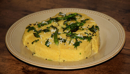 Side angle shot of Delicious Dhokla served on a bone china plate which is a yellow color sponge dish that is native to the Indian state of Gujarat 