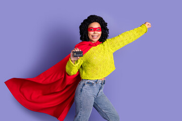 Photo portrait of lovely young lady hold credit card flying superhero dressed stylish yellow garment isolated on violet color background