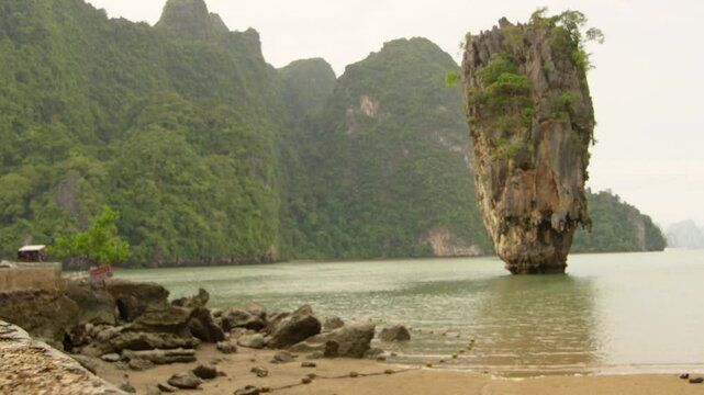 A stunning aerial shot of Khao Phing Kan, famously known as James Bond Island, located in Phang Nga Bay, Thailand. The turquoise waters gently lap against the dramatic limestone cliffs that rise verti