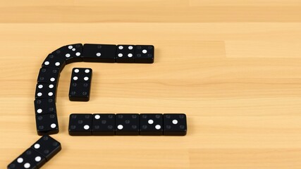 Black dominoes arranged in a chain pattern on a wooden table background, concept, strategy, arrangement