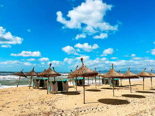 Beach Umbrellas And Green Sunbeds On Flooded Sandy Tropical Beach With Waves And Blue Cloudy Sky