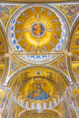 The intricate dome of the Church of Saint Sava showcases stunning gold and colorful murals, depicting religious figures in a captivating blend of artistry and spirituality.