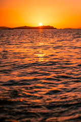 Sole al tramonto - Foto panoramica del sole che tramonta sul mare calmo e sull'isola sullo sfondo,
