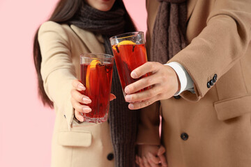 Couple with glasses of delicious mulled wine on pink background, closeup