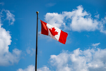 Waving Canadian flag and cloudy blue sky.