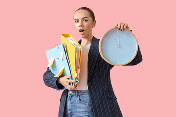 Shocked businesswoman with folders and clock on pink background