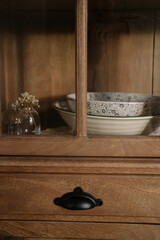 stack of vintage salad bowls on a shelf in a wooden cupboard with a soft warm sunlight. Aesthetic...