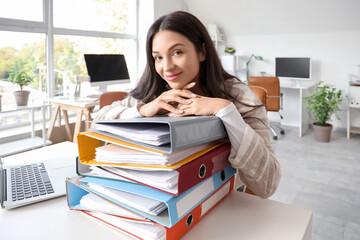 Beautiful businesswoman with folders at desk in office