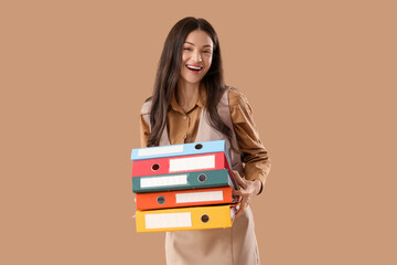 Beautiful businesswoman with folders on beige background