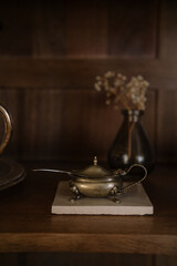 Vintage silver gravy boat, saucer and decoration on a shelf in a wooden cupboard with a soft warm...