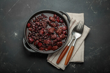 Feijoada, a traditional brazilian stew in a cast iron pot,, ready to be served with a spoon and...