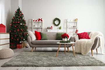 Interior of living room with sofa, armchair and Christmas plant poinsettia on table