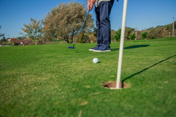 Obraz premium copyspace golf ball rolling toward the hole on the green after being hit by a unrecognized golfer
