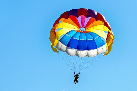 Paragliding using a parachute on background of blue sky.