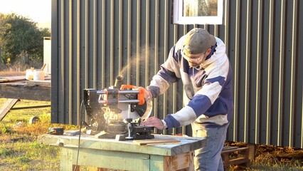 Adult bearded man sawing. Circular miter saw. Sawdust flying. Worker. Country house. Business....
