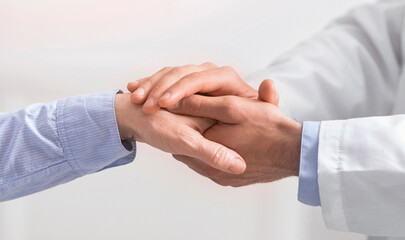 Older people healthcare support concept. Doctor holding hand of senior woman at medical visit, close up