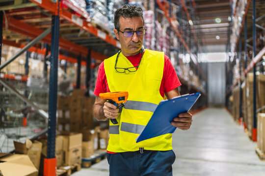 Warehouse worker scanning and checking goods with barcode reader and clipboard