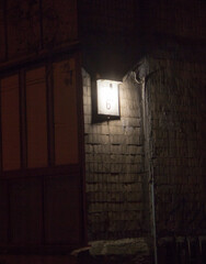 Obraz premium The house number plate is located on the corner of the building, attached to the brick wall. Light emanates from above, creating a mysterious atmosphere