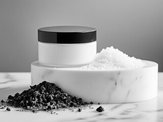 White cosmetic scrub jar standing on white podium with coal dust and salt crystals on marble table. Black and white colors. Skincare products branding background.