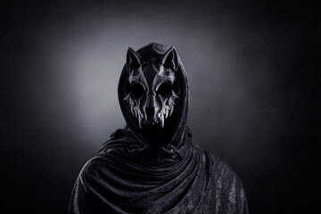 Creepy figure with animal skull at night over dark misty background
