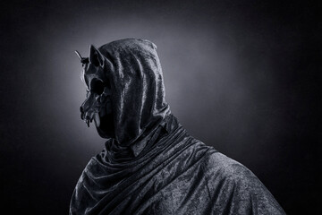 Creepy figure with animal skull at night over dark misty background