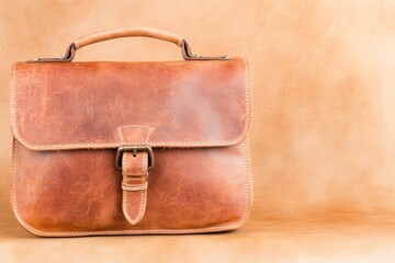 Handcrafted leather satchel with subtle red accents on a textured brown surface