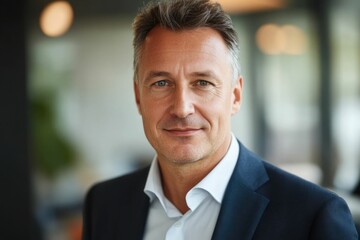 Fototapeta premium Close-up headshot Confident European mature, good looking middle aged leader, male businessman CEO on blurred office background. Handsome senior European businessman smiling at camera