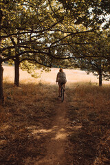 Fototapeta premium Woman riding bicycle in grass and autumn forest