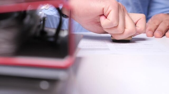 Office worker stamping a document with wooden stamper