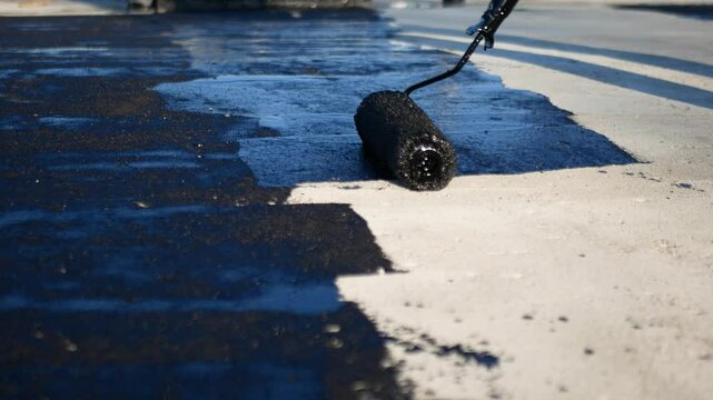 Flat roof waterproofing preparation using mastic primer close up by professionals