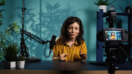 Happy online show host hitting the record button on professional camera, using microphone to talk...
