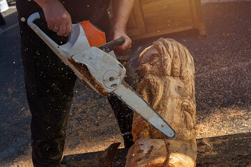 Man using chain saw to create wood carving