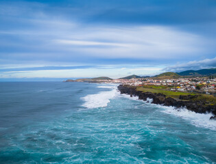 Ribeira Grande on the Atlantic ocean coast in Sao Miguel island, Azores, Portugal. Aerial drone view of city, cliffs and wavy ocean