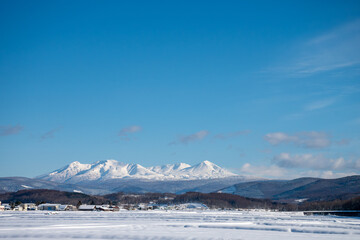 Fototapeta premium 冬の晴れた日の雪山と積雪の水田 