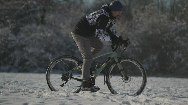 Man struggles through deep snow on off-road path, battling rough terrain and snowdrifts. Despite harsh conditions and cold, he pushes forward with determination, braving elements in winter landscape. 