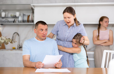 Obraz premium Wife yells at her husband who has not paid the loan. Children are upset and scared