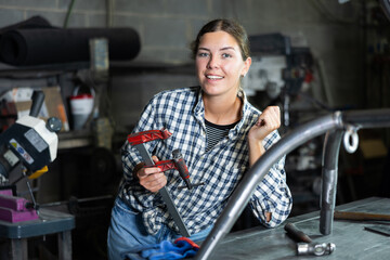 Portrait of young female worker at metallurgical plant with a caliper in her hands